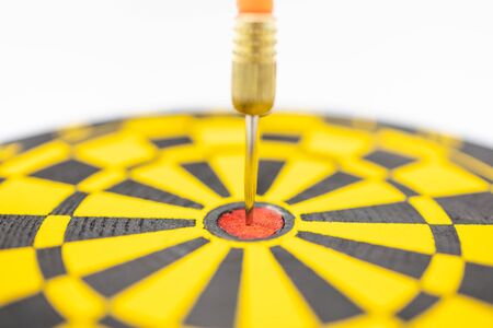 Game, Business, Planning and Target Concept.  Close up of  dart stab on center of black and yellow board on white background.の写真素材