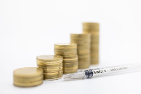Close up of insulin syringe for control blood sugar level with stack of gold coins using as...