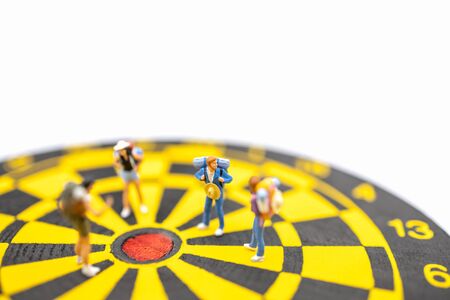 Travel, Planning and target Concept. Close up of group of traveler miniature figures people with backpack standing on black and yellow dart board on white background and copy spaceの写真素材