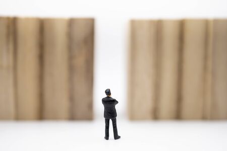 Business, Management, Planning, Succession and strategy Concept. Close up of businessman miniature figure standing in front of wooden block wall on white background.の写真素材