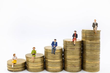 Succession, Finance, Business, Money, Security and Saving Concept. Close up of group of businessman and woman miniature figures sitting on top of stack of gold coins on white background and copy space.の写真素材