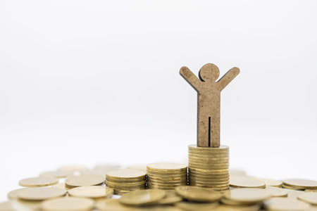Business, Finance, Money Saving and Success Concept. Close up of wooden man figure  on top of stack...