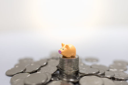 Money, Business, Finance and Saving Concept. Close up of miniature pig figure on top of stack of...