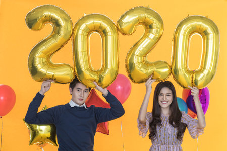 2020 New Year Concept. Portrait of smiling beautiful young asian woman and handsome man holding...