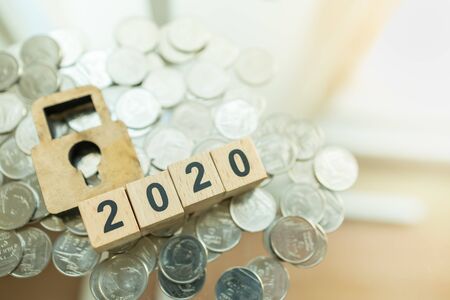 2020 Business, Planning, Finance and Money Security Concept. Close up of Wooden number block and master key lock icon symbol on pile of coins with copy space.の写真素材