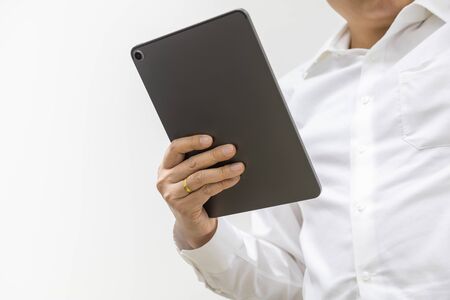 Asian businessman wearing white shirt holding a computer tablet on white background with copy space.の写真素材