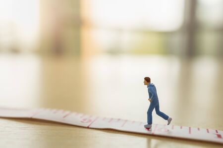 Sport and fitness concept. Close up of man runner miniature figure people running on measure tape on wooden table with copy spaceの写真素材