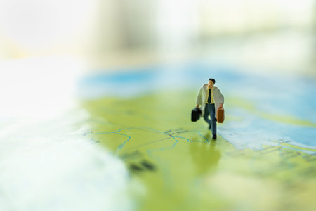 Business Trip and Travel Concept. Close up of businessman miniature figure with handbag suitcase...