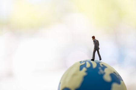 Global Business and Planning Concept. Close up of businessman miniature figure people walking on world mini ball with copy space.の写真素材