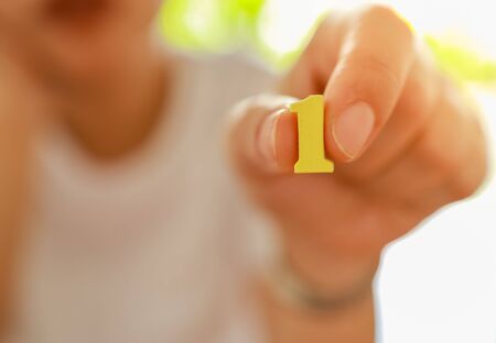 Business and Target Concept. Close up of business woman holding yellow wooden number 1の写真素材