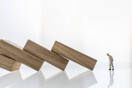 Crisis and failure in Business, Insurance and Risk Management Concept. Close up of businessman miniature figure people looking to wooden block  the collapse of fall in line, with copy space.の写真素材
