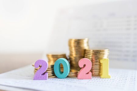 2021 New year, Business, Saving and Planning Concept. Close up of colorful wooden number on bank passbook with stack of gold coins with copy space.の写真素材