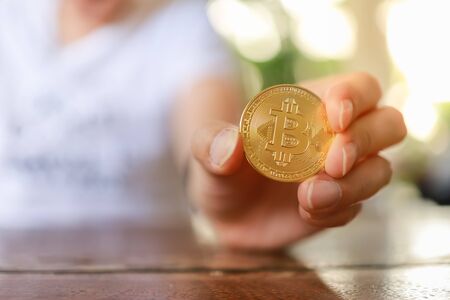 Business , Money, Technology and  cryptocurrency Concept. Close up of man hand holding gold bitcoin coins on wooden table.の写真素材