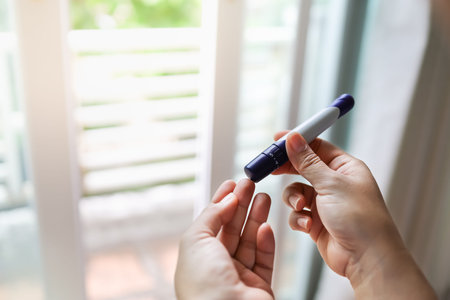 Close up of woman hands using Glucose meter on finger to check blood sugar level in bed room in the...
