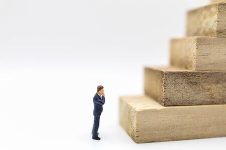 Business Planning and Work Concept. Close up of businessman miniature figure people looking to stack of wooden block  on white background and copy space.の写真素材