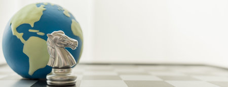 Global, Sport board game, Business and planning Cover Page concept. Closeup of Knight silver chess pieces with mini world ball on chessboard with copy space.の写真素材