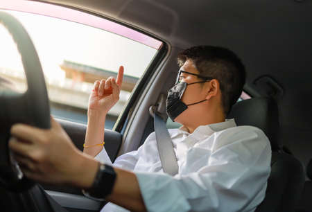 Business man with wearing face mask driving a car into drive through service and show one  finger to order something.の写真素材