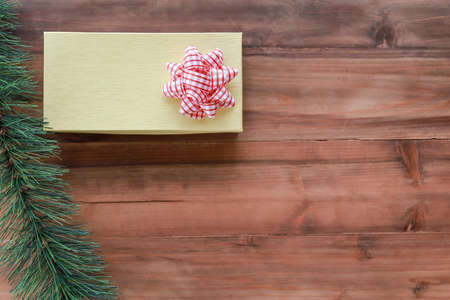 New Year, Christmas and Holiday Season Concept. Top view of beautiful yellow gift box with mockup tree on old wooden plank with copy space.の写真素材