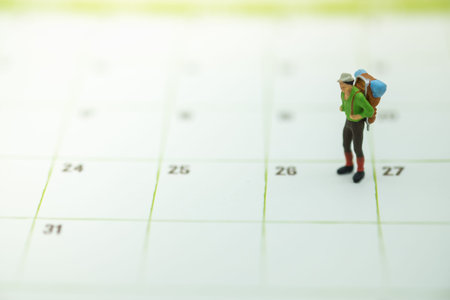 Travel and Planning Concept. Traveler miniature figure people with backpack standing on calendar.