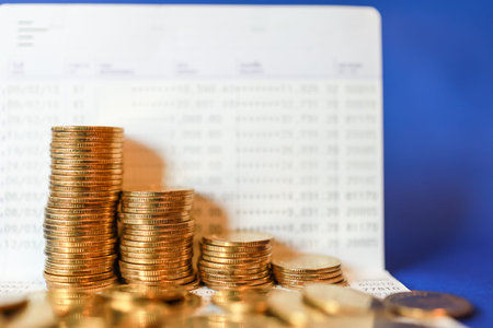Business Money and Saving Concept. Closeup of stack of gold coins on bank passbook on blue background.の写真素材