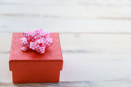 Christmas, New Year Party Concept. Closeup of beautiful red gift box on white wooden table.の写真素材