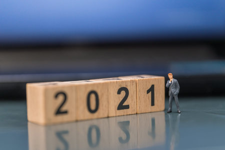 2021 New Year, Business concept. Businessman miniature figure people standing with wooden number...