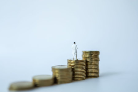 Business and Healthcare Concept. Docter miniature figure people standing on top of stack of coins on...
