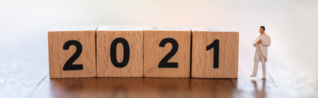 2021 New Year, Healthcare Cover Page concept. Closeup of docter miniature figure people standing with wooden number block on wooden table.の写真素材