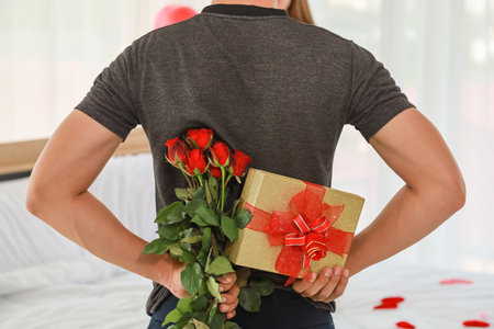 Couple, Love and Valentine's Day Concept. Back of man surprised his girlfriend with a gift box and rose in bedroom.の写真素材