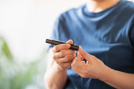Close up of woman hands using lancet on finger to check blood sugar level by Glucose meter. Use as Medicine, diabetes, glycemia, health care and people concept.の写真素材