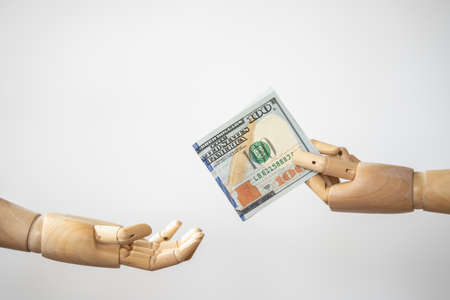 Money Financial and Payment Concept. Closeup of wooden hand model holding and give a 100 US Dollar bank note to other hand.の写真素材