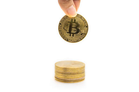 Business , Money, Technology and  cryptocurrency Concept. Closeup of gold bitcoin coin with finger holding and putting down to top of stack of coins isolated on white background.の写真素材