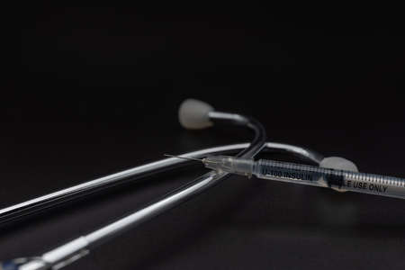 Closeup of Insulin syringe with medical stethoscope to use control blood sugar level on black background. Use as Medicine, diabetes, glycemia, health care and people concept.の写真素材