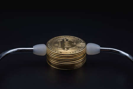 Business , Money, Technology and  cryptocurrency Concept. Closeup of gold bitcoin coins with medical stethoscope on black background.の写真素材