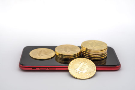Business , Money, Technology and  cryptocurrency Concept. Closeup of gold bitcoin coins on red mobile smartphone with white background.の写真素材
