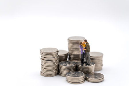 Money, Financial, Business and Family concept, Miniature figures man, woman and child stand on top of stack of coins on white background.の写真素材