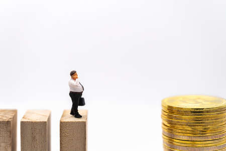 Business, Money Investment and Planning Concept. Fat businessman miniature figure people make a phone call and  walking on wooden block to stack of gold bitcoin coins on white background.の写真素材