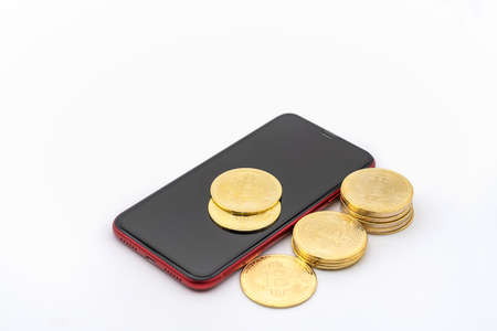 Business , Money, Technology and  cryptocurrency Concept. Closeup of gold bitcoin coins on red mobile smartphone with white background.の写真素材