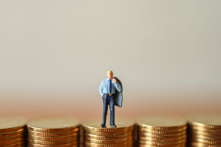 Business Money and Financial Concept. Businessman miniature figures people standing on top of stack of gold coin wiht copy space.の写真素材