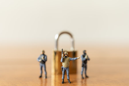 Business and Security Concept. Group of soldier or Police miniature figure people with machine gun standing with golden master key lock on wooden table.の写真素材