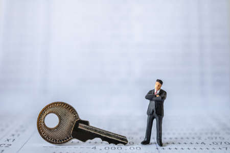 Business and Security Concept. Businessman miniature figure people standing with silver key on bank passbook.の写真素材