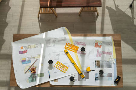 Business, Engineer, Architecture and Work place concept. Top view of architectural building blueprints with ruler, pencil, measurement, architect equipment tool and paper cup of coffee on wooden table.の写真素材