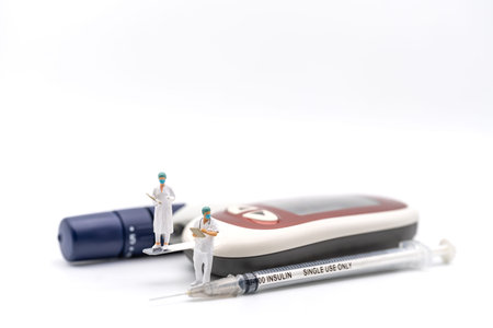 Two doctor miniature figure with patient file standing on glucose meter with lancet and Insulin...