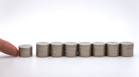 Money and Saving Concept. Closeup of finger to put a stack to group of stack of silver coins on white background.の写真素材
