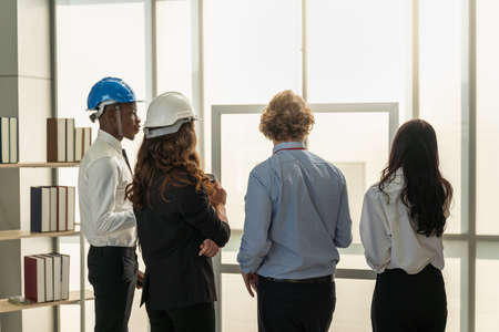 Diversity Business and Engineering and Construction Concept Back of group of engineer, businessman and businesswoman meeting with building  structure plan blueprint in office.の写真素材
