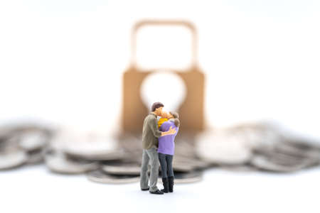 Money, Financial, Business Security and Family concept. Parent and child miniature figures hug and kiss together standing with pile of coins and master key lock icon on white background.の写真素材