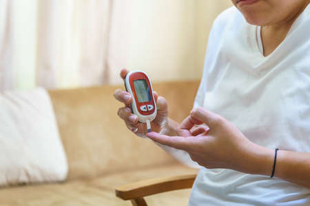 Close up of man hands using Glucose meter on finger to check blood sugar level. Use as Medicine, diabetes, glycemia, health care and people concept.の写真素材