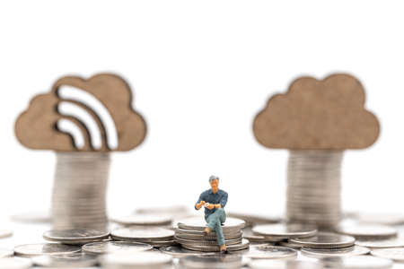 Business Money, Financial and Work Concept. Businessman miniature figure people sitting on stack of silver coins with wooden cloud icon as background.の写真素材