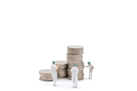 Business, Money Healthcare Concept. Group of docter miniature figure people wearing cap and face mask with patient file standing with stack of coins on white background.の写真素材