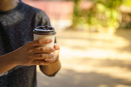 Closeup of woman hand holding disposable take away paper cup of hot coffee with copy space.の写真素材